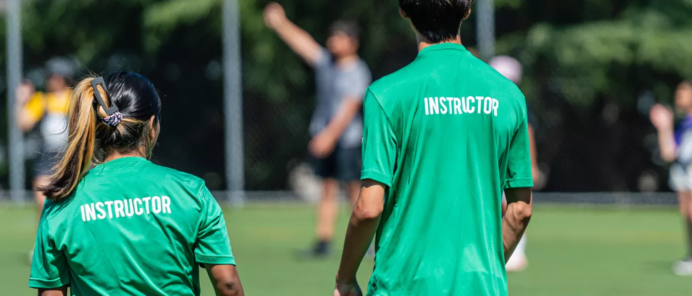 two instructors in green shirts looking at the field